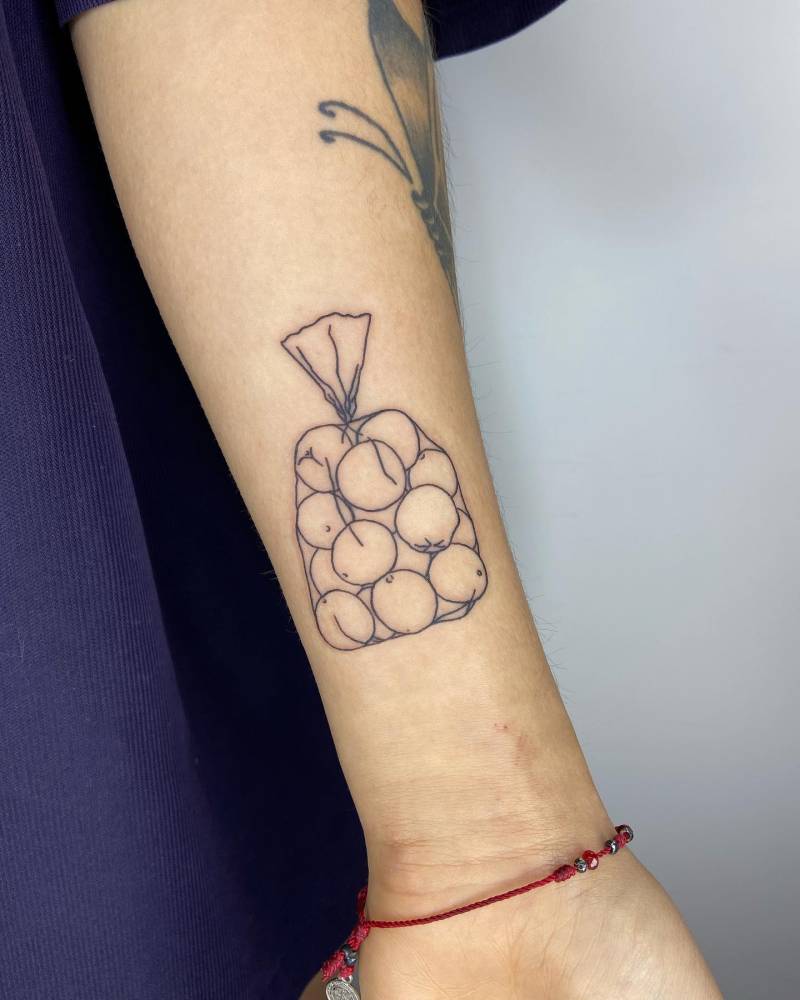 Hand poked orange bag tattoo located on the inner forearm.