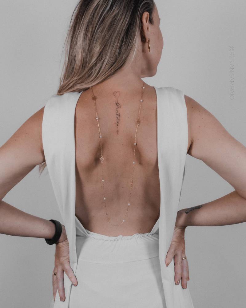 Tatuagem da palavra "gratidão" feita na parte superior das costas.