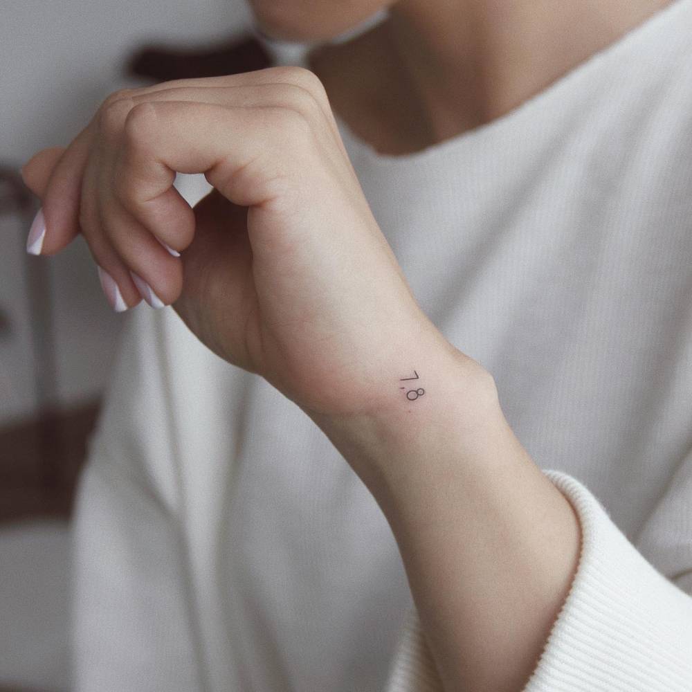 Tiny "7.8" lettering tattoo located on the wrist.