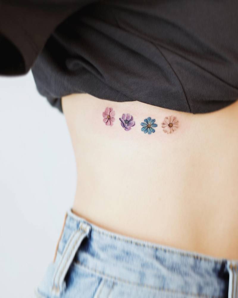 Micro-realistic flowers tattooed on the rib.