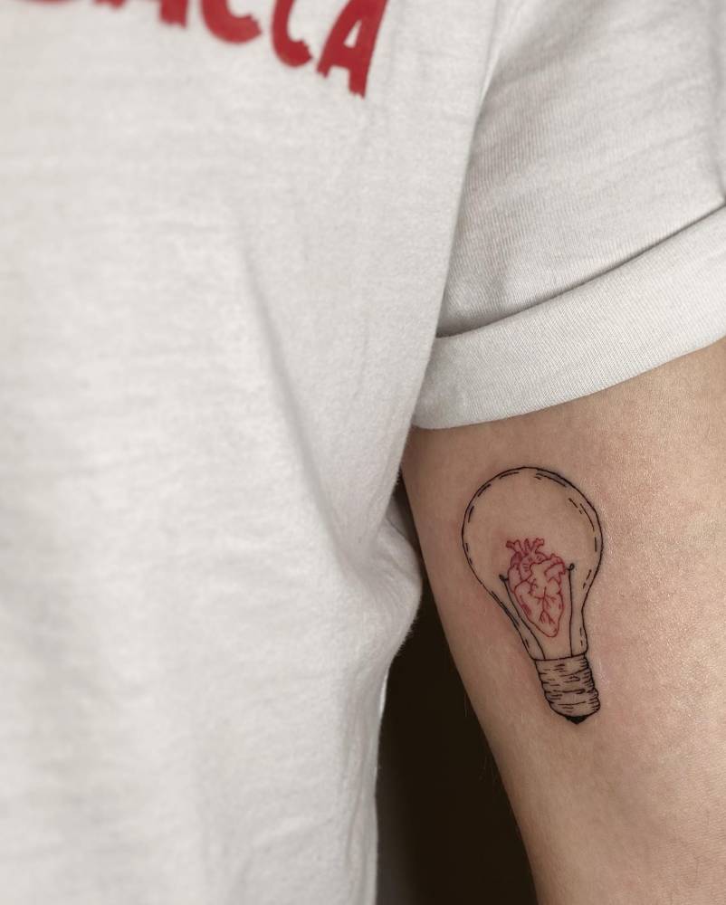 Lightbulb and heart tattoo located on the inner arm.