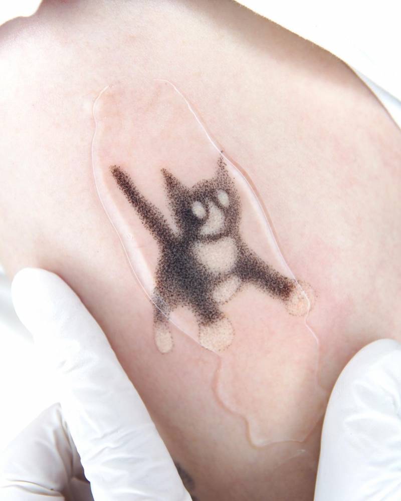 Hand poked tuxedo cat tattoo located on the upper arm.