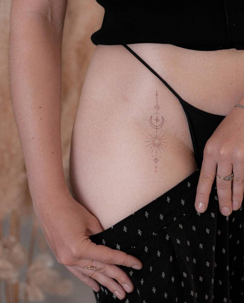 Ornamental sun and moon tattoo located on the pelvis.