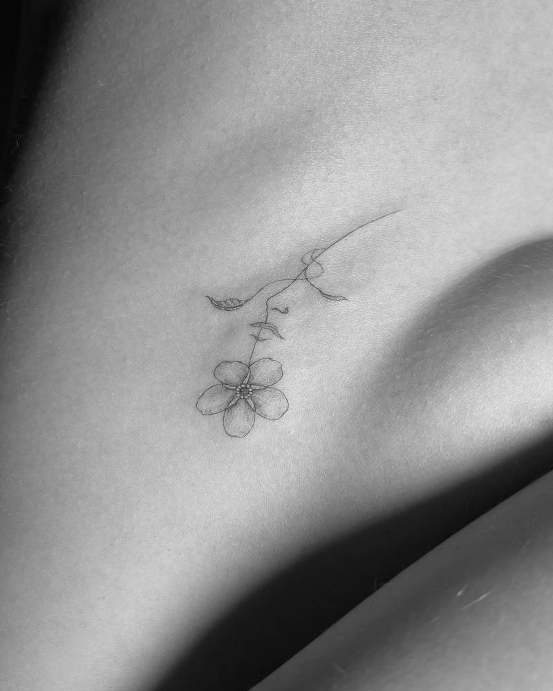 Single needle flower face tattooed on the side boob.