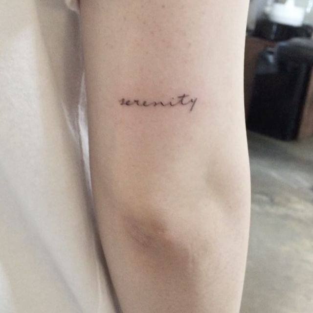 Tattoo of the word "serenity" located on the tricep.