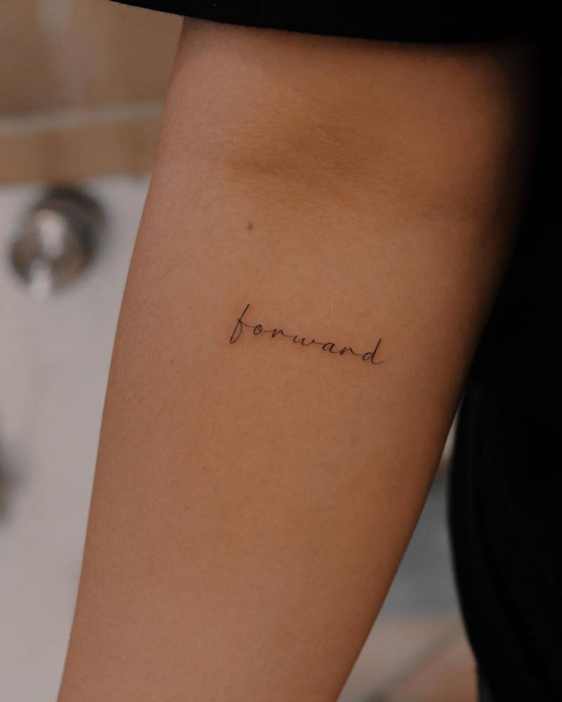 Tattoo of the word "forward" done on the inner forearm.