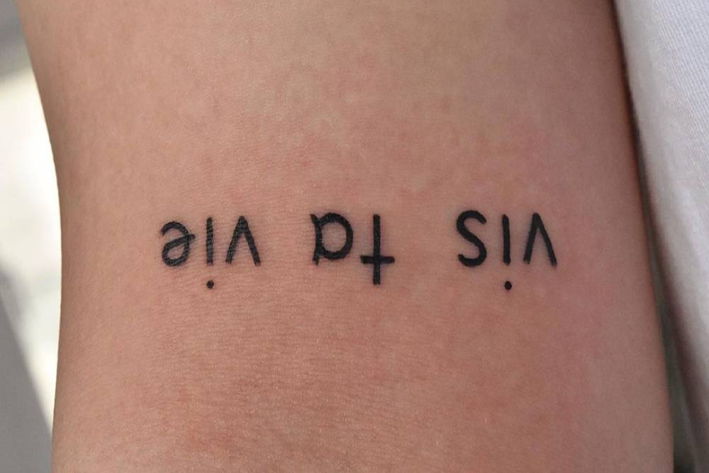 "Vis ta vie" lettering tattoo done on the bicep.