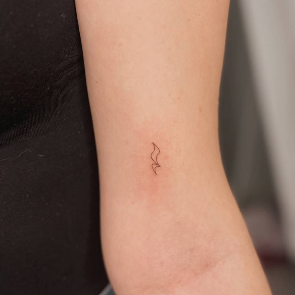 Tiny minimalistic quarter rest tattoo placed on the inner arm.