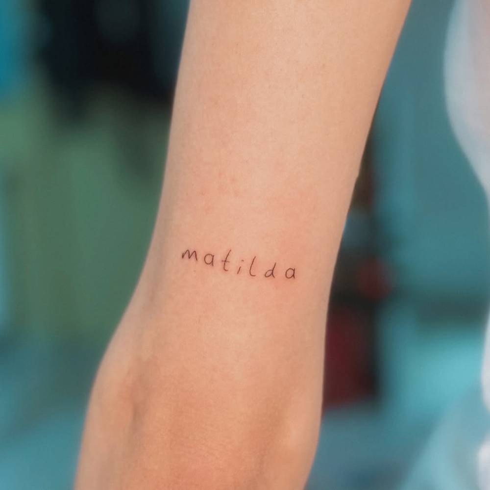 Handwritten font name "Matilda" tattooed on the tricep.