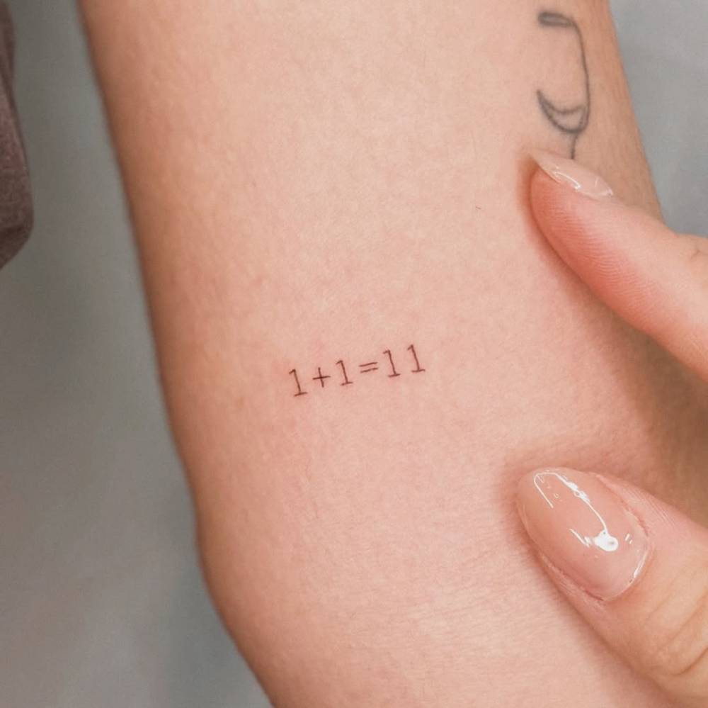 Equation tattoo in typewriter font located on the inner arm.