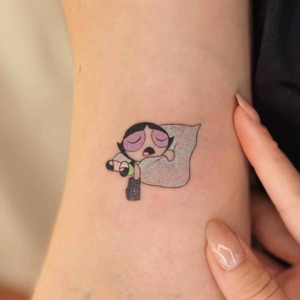 Cartoon style sleeping Buttercup tattoo located on the inner arm.