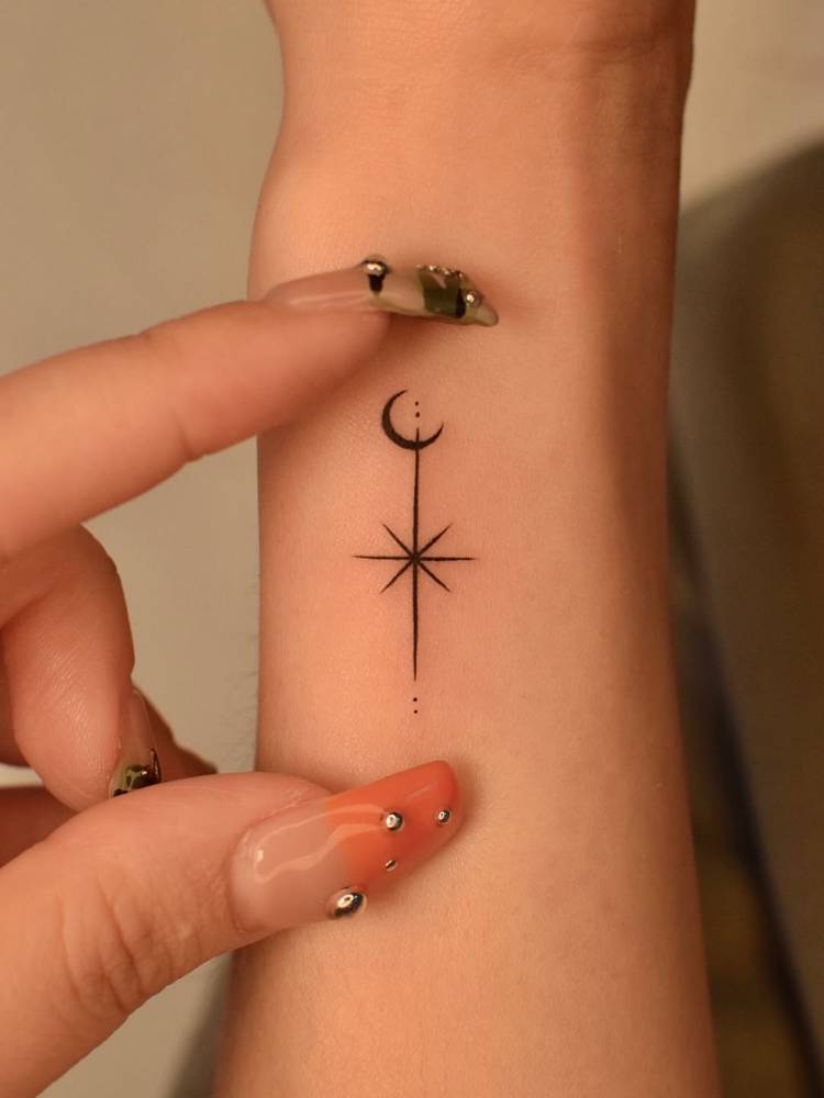 Crescent moon and north star tattoo located on the wrist.