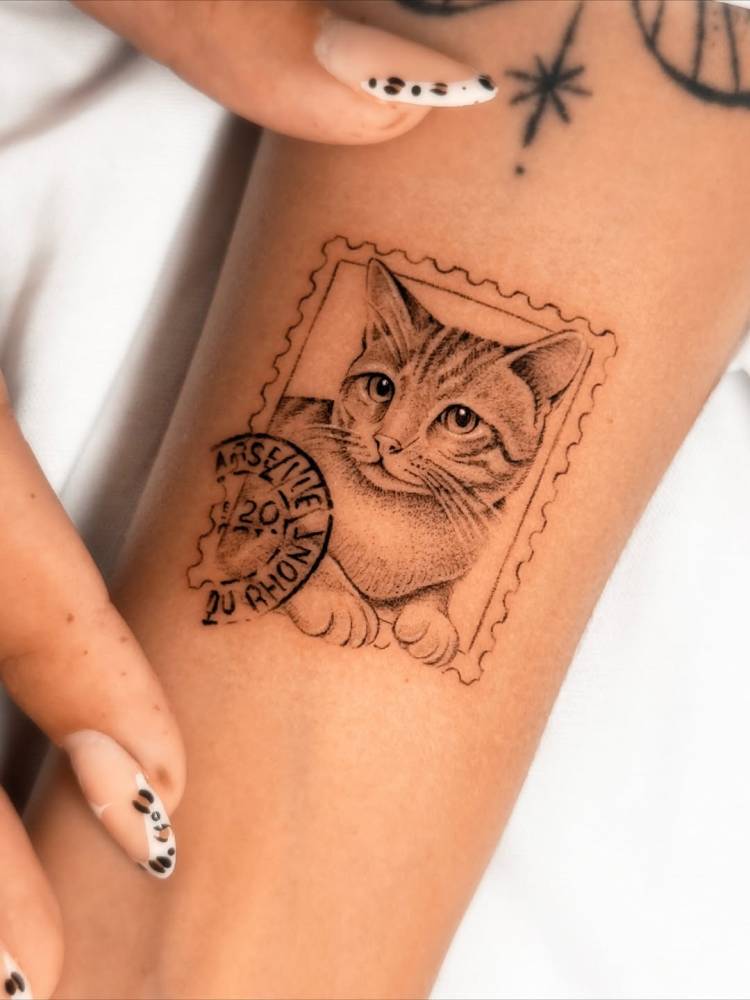 Cat stamp tattoo in micro-realistic style placed on the wrist.