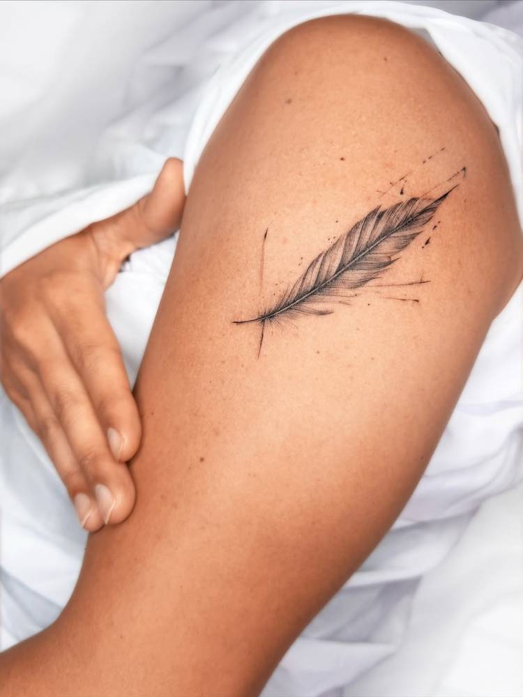Watercolor style feather tattoo located on the upper arm.