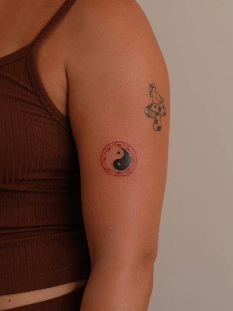 Yin Yang tattoo in illustrative style located on the upper arm.