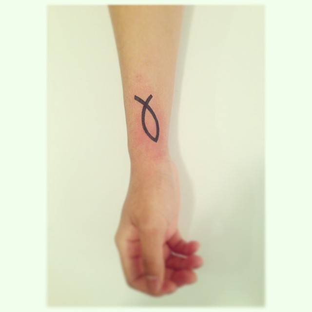 Jesus fish tattoo in minimalistic style located on the wrist.