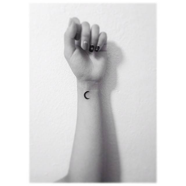 Crescent moon tattoo placed on the wrist, done in minimalistic style.