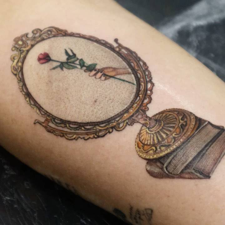 Micro-realistic mirror tattoo on the forearm.