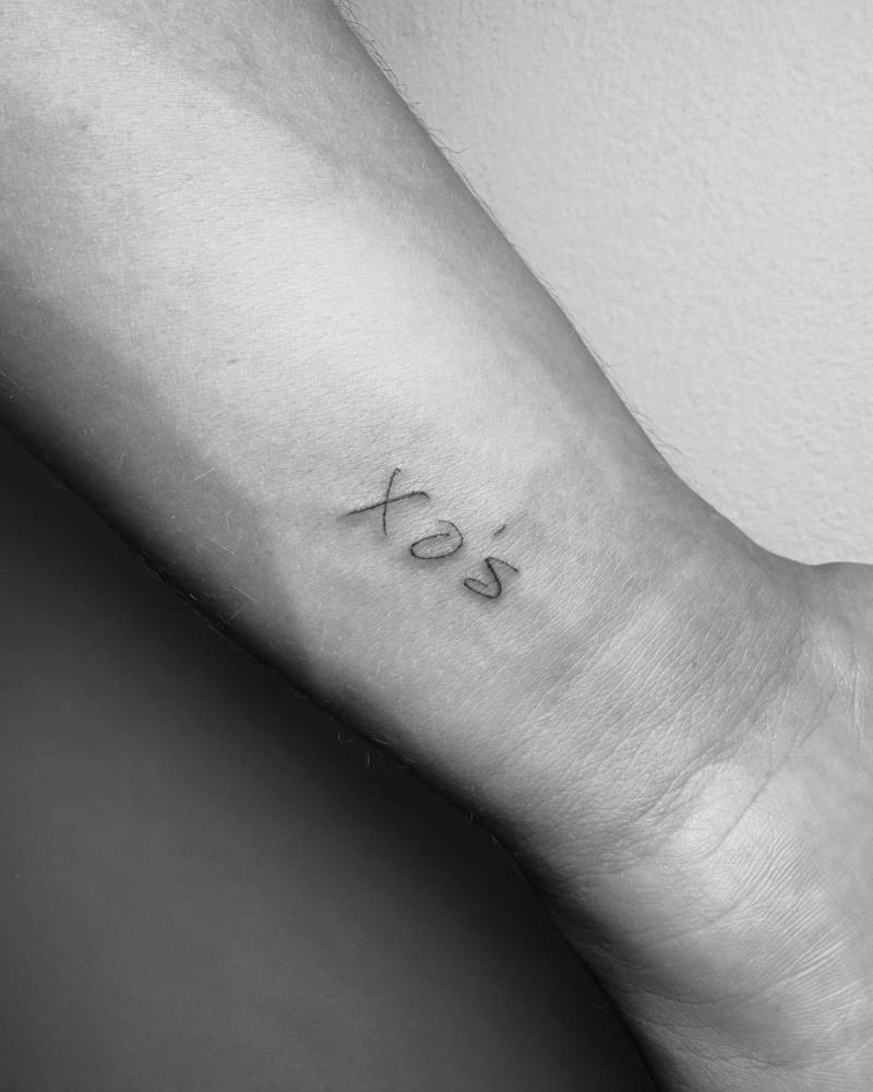 "XO's" tattoo in handwritten font located on the wrist.