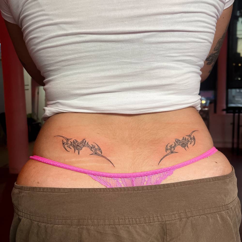 Individual matching tribal tattoos located on the lower back.