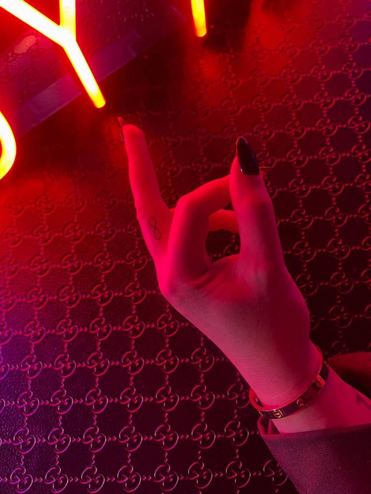 Tiny minimalistic infinity symbol tattoo located on the finger.