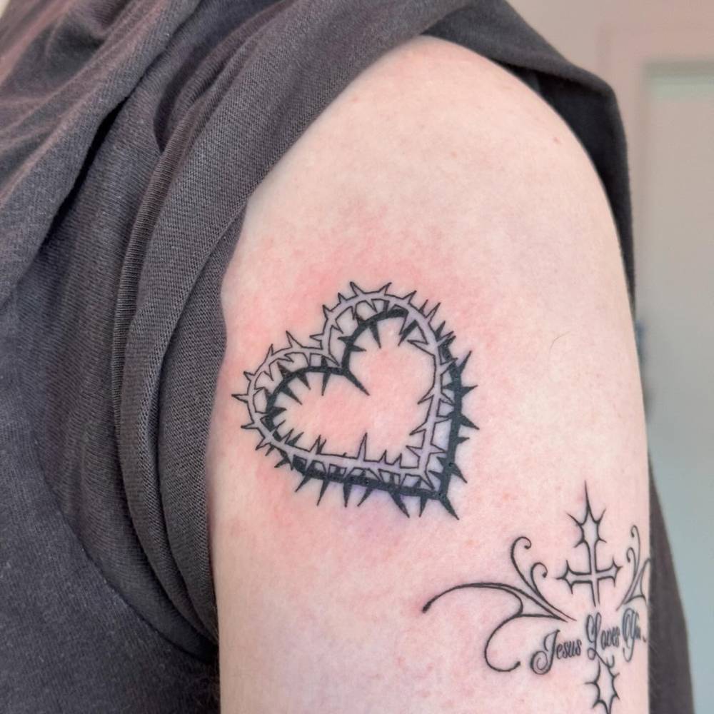 Thorns heart tattoo in illustrative style located on the upper arm.