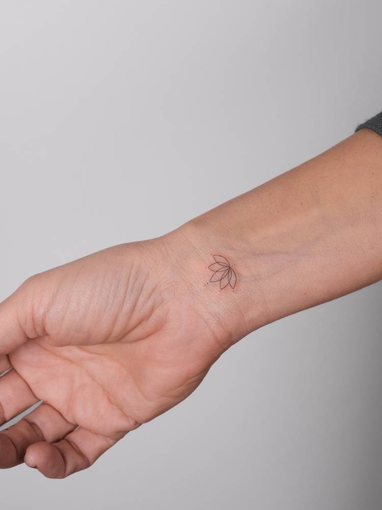 Lotus flower tattoo in fine line style done on the wrist.