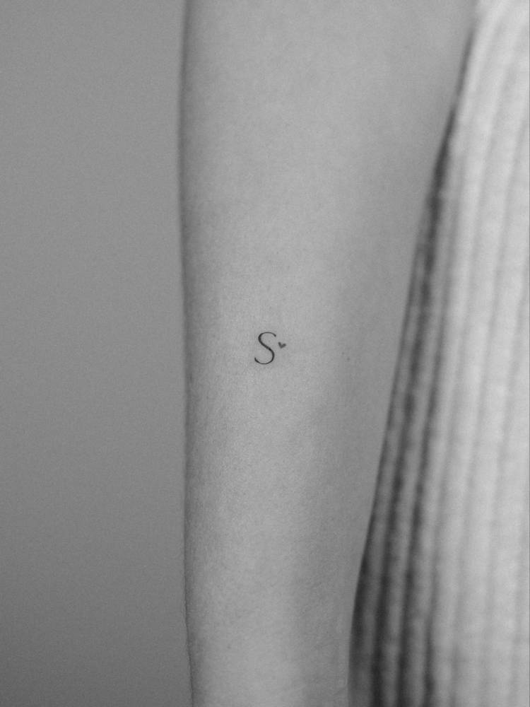 Tiny letter "S" and heart tattoo placed on the forearm.