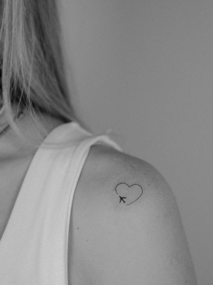 Airplane and heart tattoo done on the shoulder, minimalistic style.