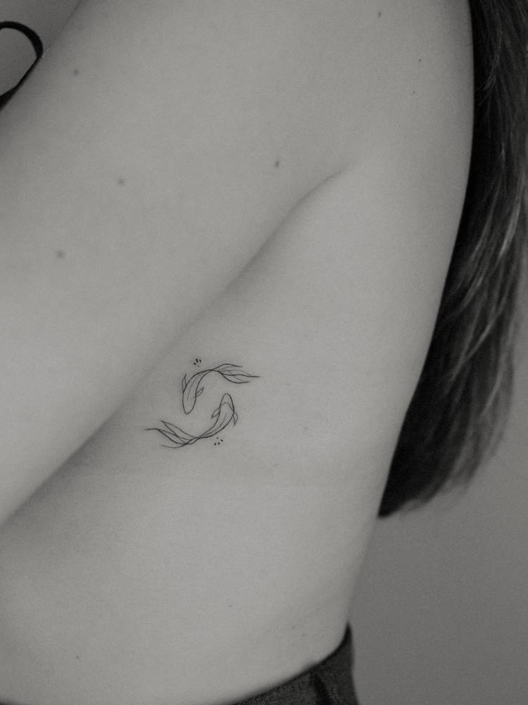 Two opposite fish tattoo located on the side boob.