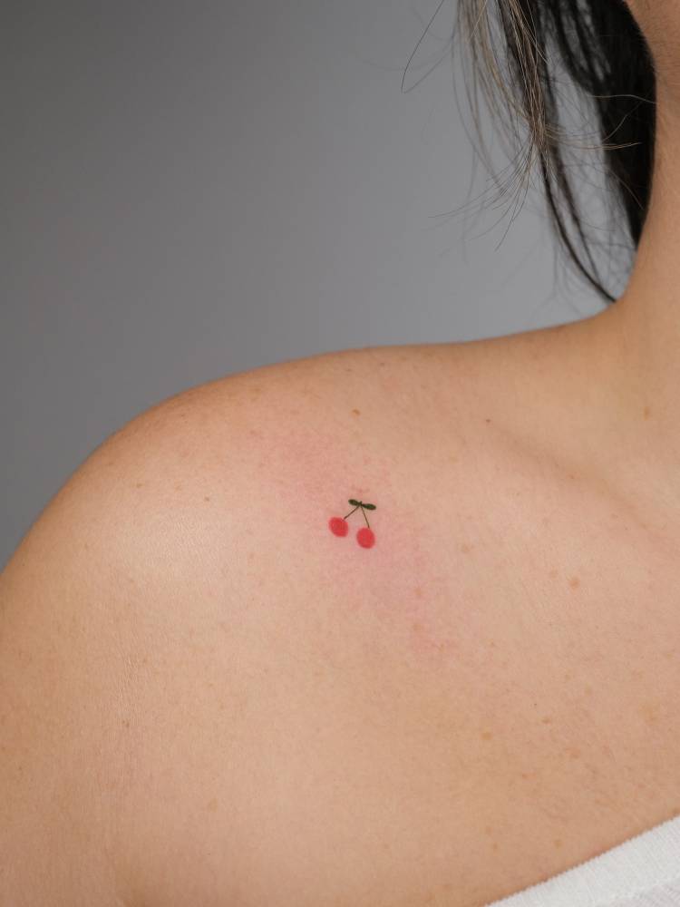 Tiny minimalistic cherries tattooed on the shoulder.