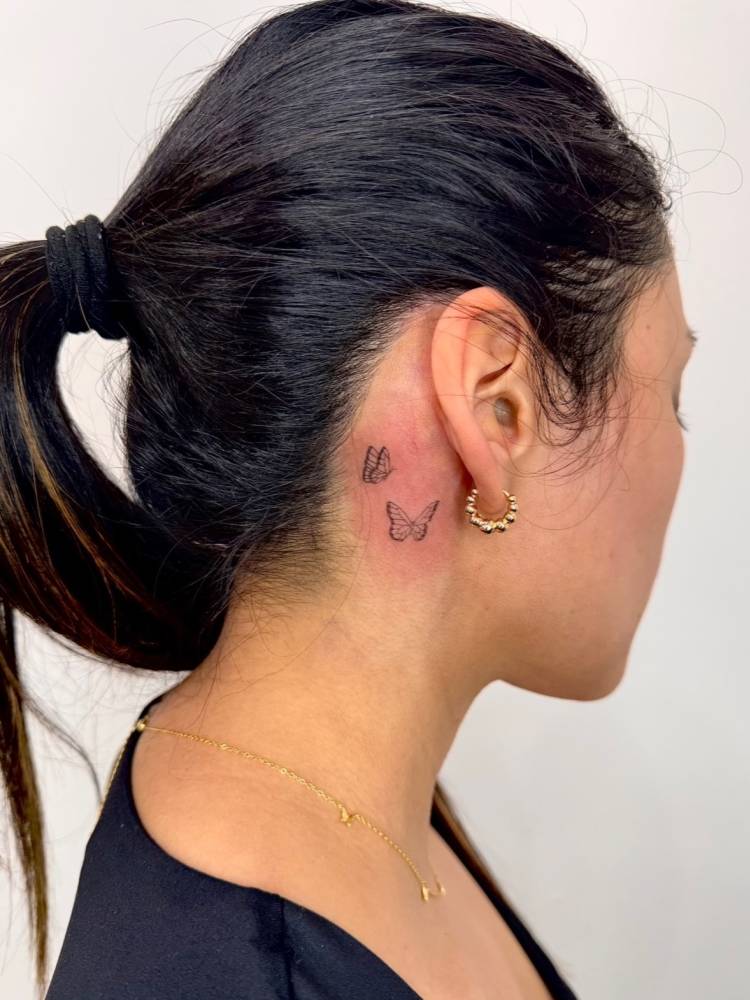 Single needle butterfly couple tattoo located behind the ear.
