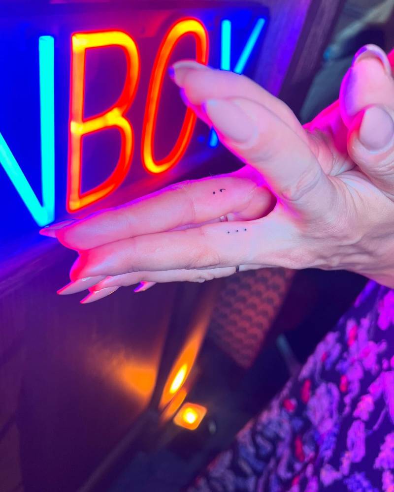 Dots and semicolon tattoos located on the fingers, minimalistic style.