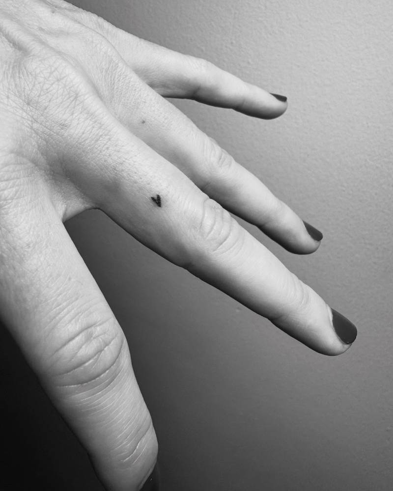 Tiny minimalistic heart tattooed on the finger.