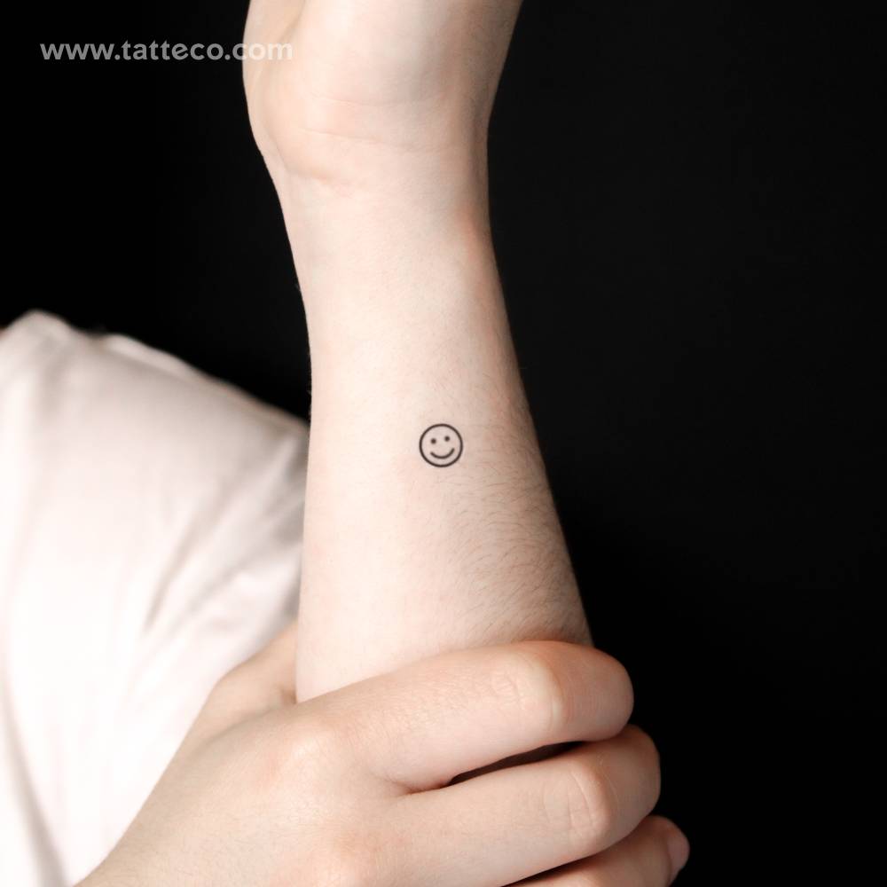 Minimalist smiley semi-permanent tattoo located on the wrist.