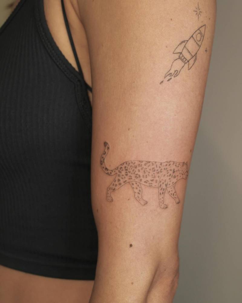 Fresh leopard and healed rocket tattoos located on the upper arm.