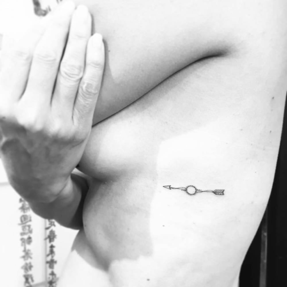 Minimalistic arrow tattoo located on the side boob.