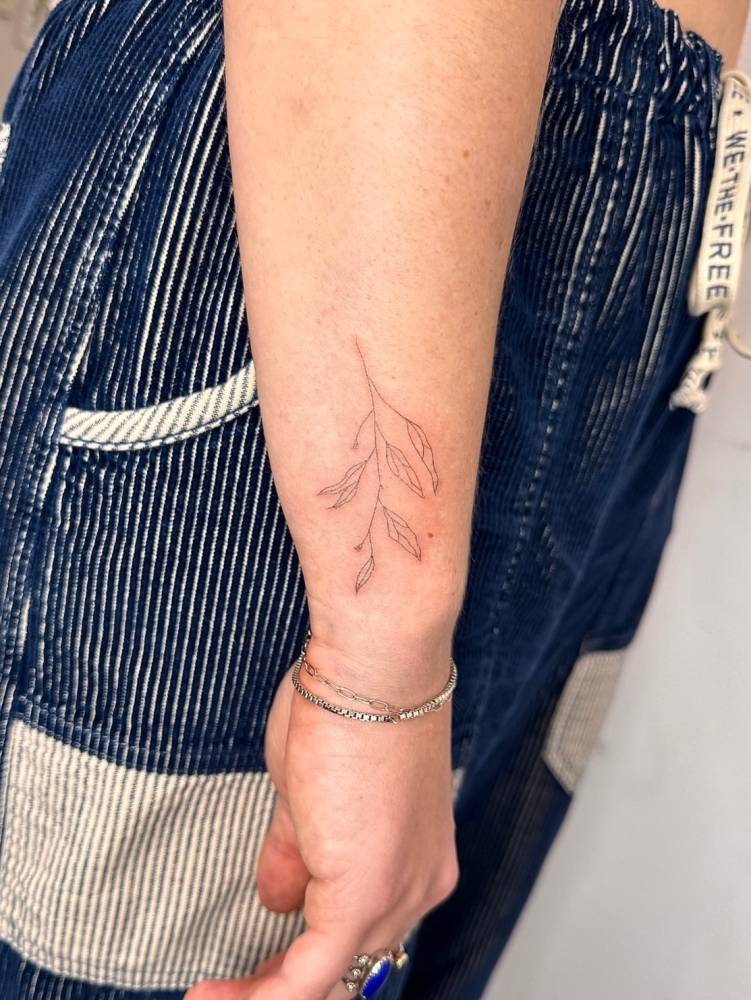 Branch tattoo in fine line style located on the wrist.