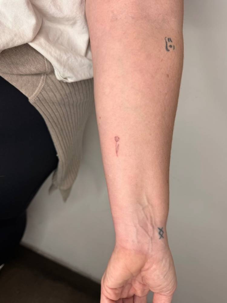 Tiny single needle tulip flower tattooed on the inner forearm.