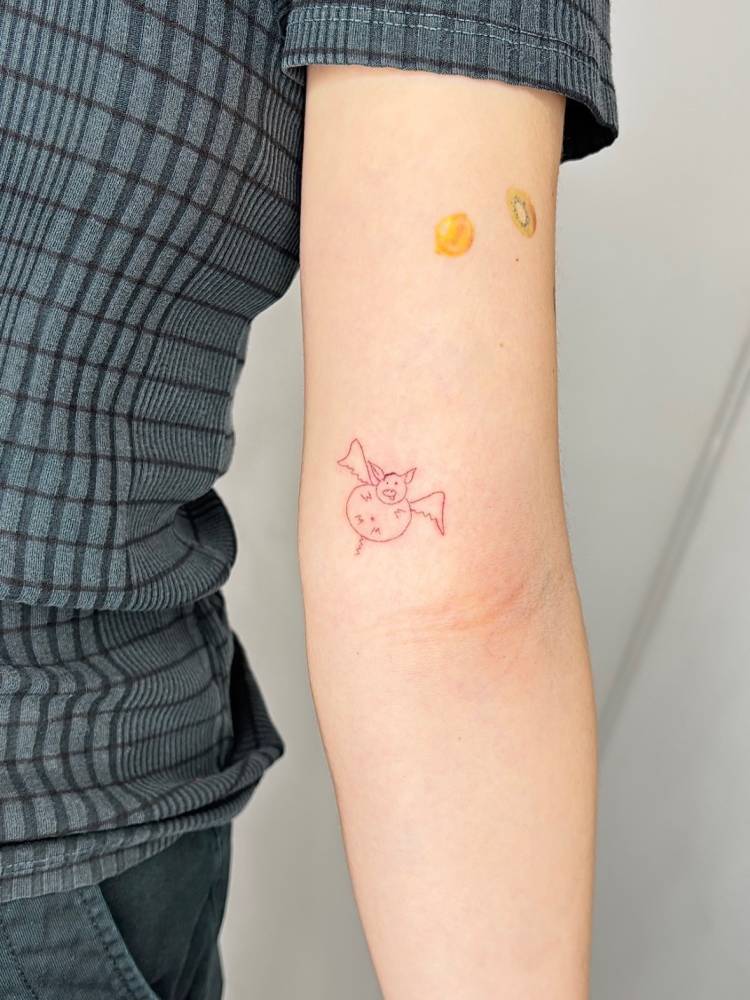 Child drawing bat tattoo located on the inner arm.