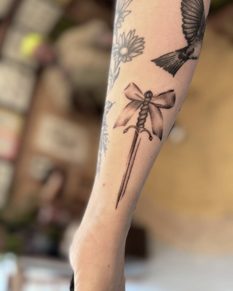 Dagger and ribbon tattoo in illustrative style.