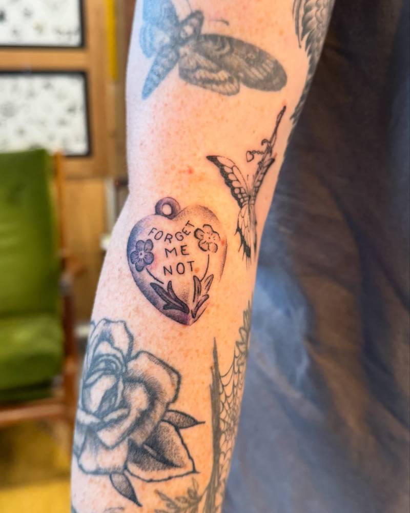 Heart pendant tattoo located on the forearm.