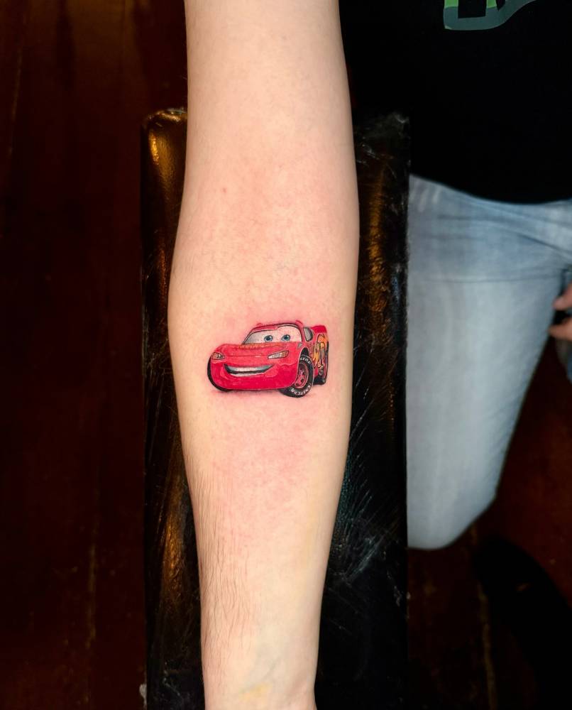 Lightning McQueen tattoo in cartoon style done on the inner forearm.