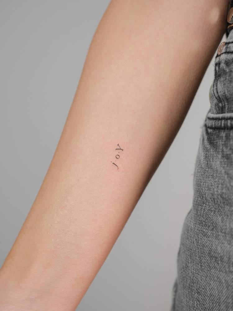 Lettering tattoo of the word "joy" located on the inner forearm.