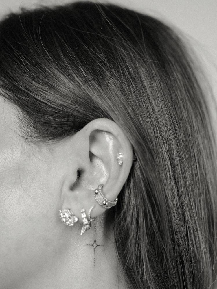 Minimalistic style star tattoo placed behind the ear.