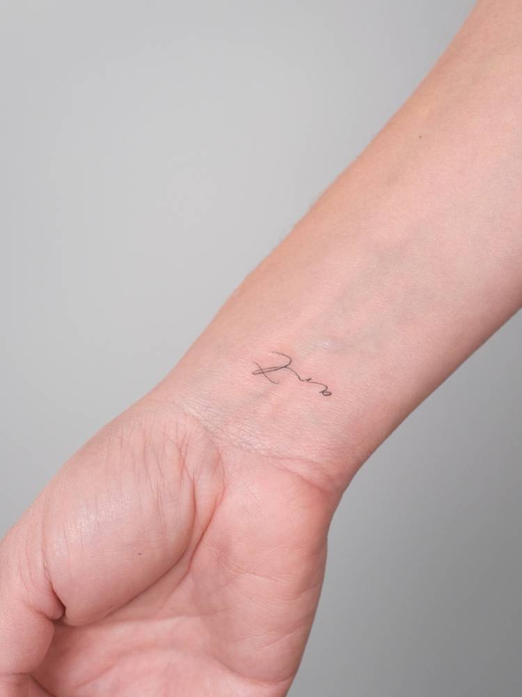 Lettering tattoo of the word "art" located on the wrist.