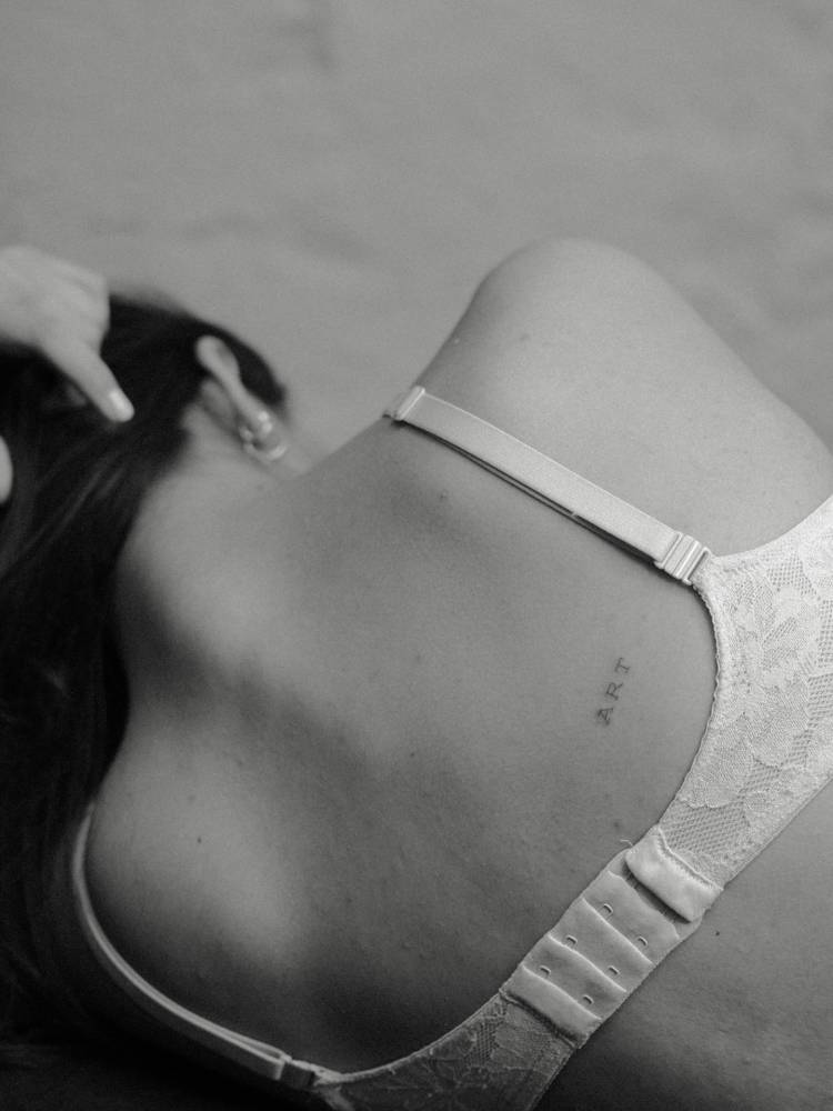 Typewriter font word "art" tattooed on the back.