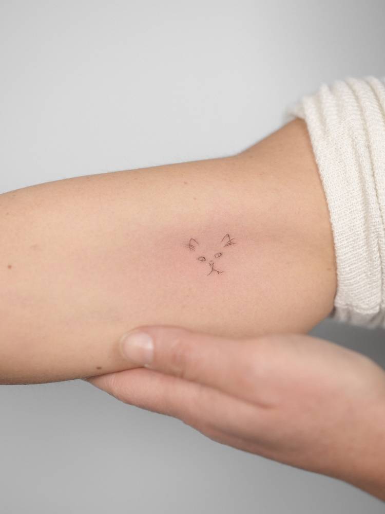 Cat portrait tattoo in minimalistic style located on the inner arm.