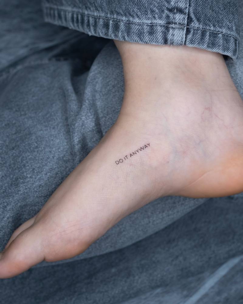 "Do it anyway" lettering tattoo located on the foot.