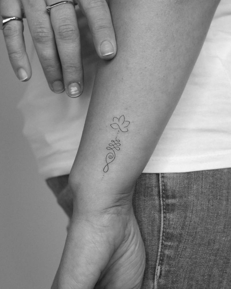 Lotus unalome tattoo located on the wrist, done in fine line style.